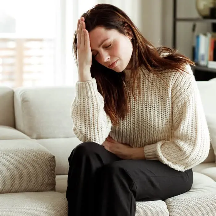 A woman holding her jaw, suffering from TMJ pain.